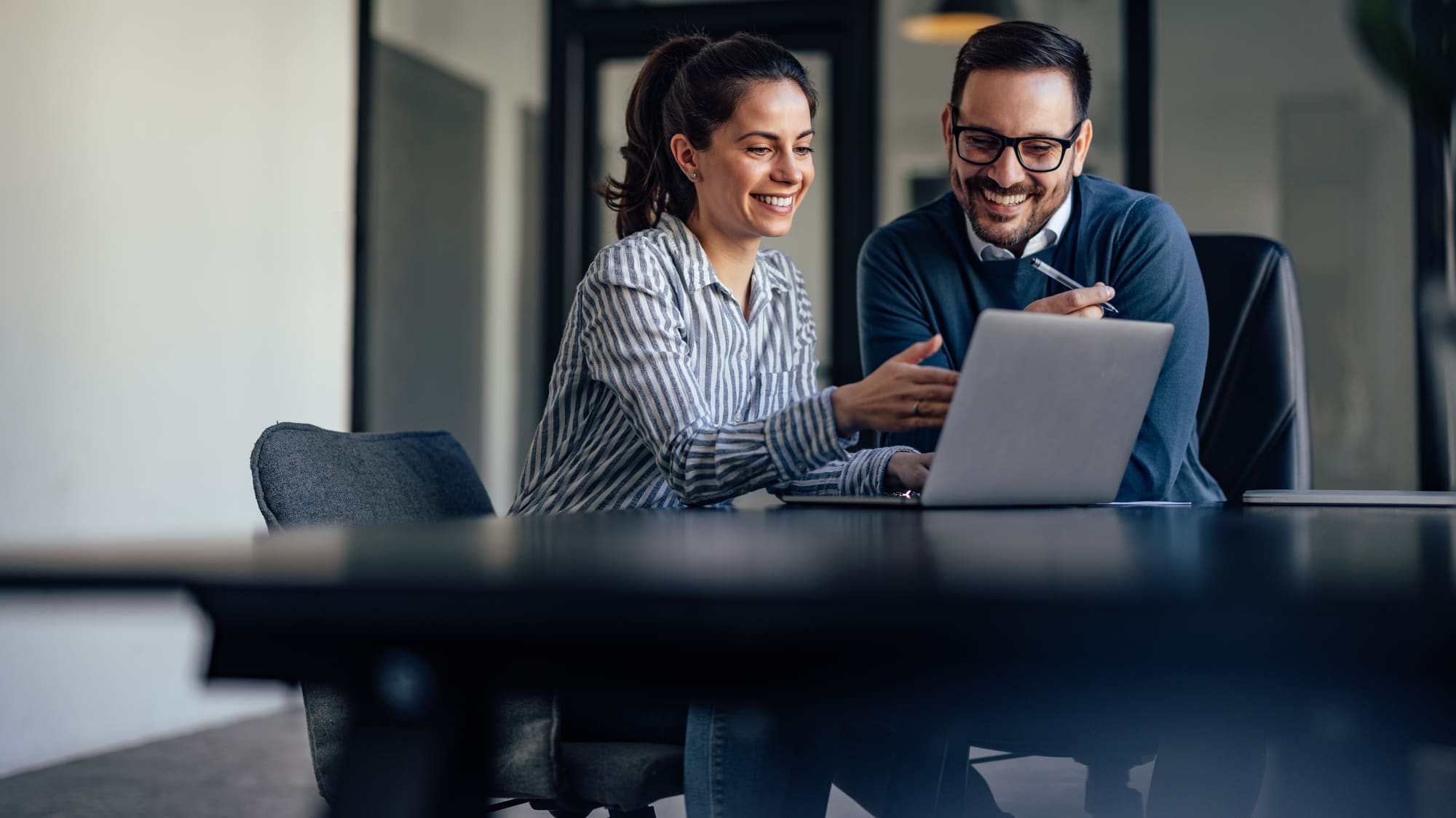 Dos personas revisando juntas un plan financiero en una laptop, sonriendo